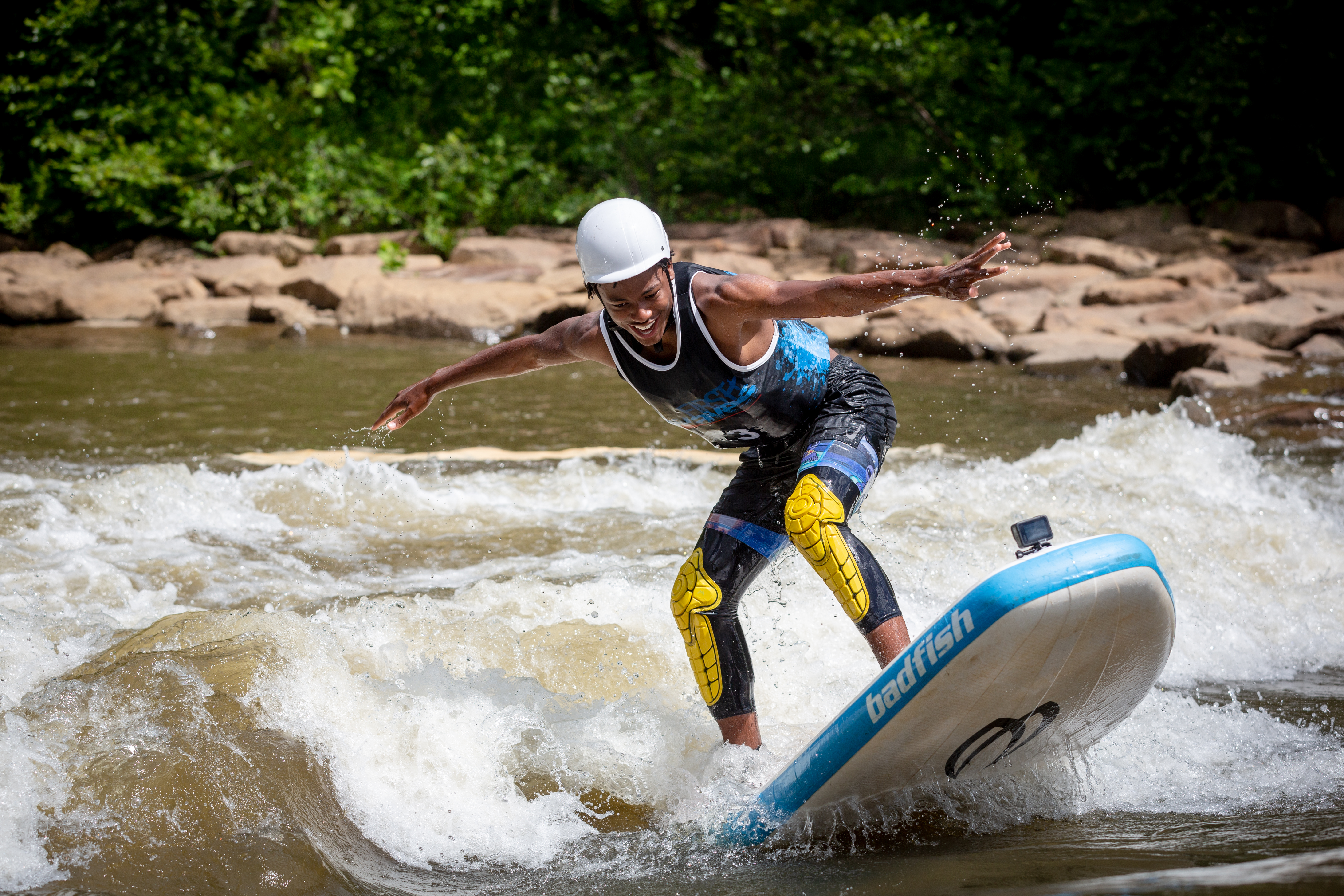 A teenager surfs on a river wave using a paddle board